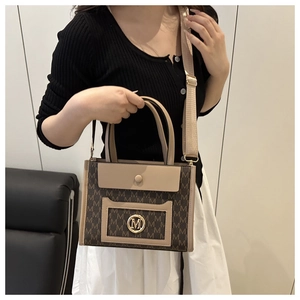 Detail of tote bag with gold M metal logo and detachable wide woven shoulder strap