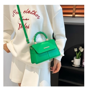 Petit sac carré vert avec poignée torsadée porté par un mannequin dans une pièce moderne