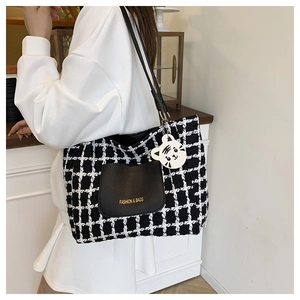 Detail of checkered tote bag featuring a leather front pocket and tiger head charm