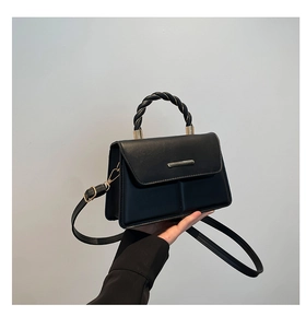 Détail du sac en similicuir noir avec poignée tressée et fermoir métallique doré