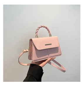 Détail du sac à bandoulière rose clair avec poignée tressée et accent métallique élégant
