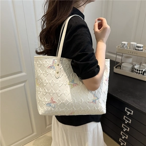 White quilted tote bag with colorful butterfly embroidery and leather shoulder strap