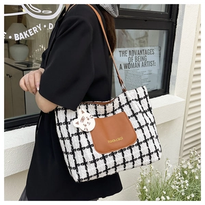 Detail of checkered tweed tote bag with brown leather pocket and cute cat charm