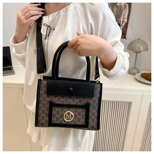 Detailed close-up of a brown monogram tote bag with gold M logo and adjustable black strap