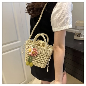 Detail of floral woven bucket bag with drawstring liner and crossbody strap