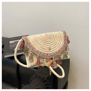 Détail d'un sac bohème en paille tressée avec motifs colorés et longues franges déco