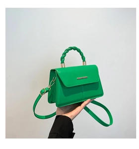 Détail d'un sac bandoulière vert vif avec poignée torsadée et accents dorés