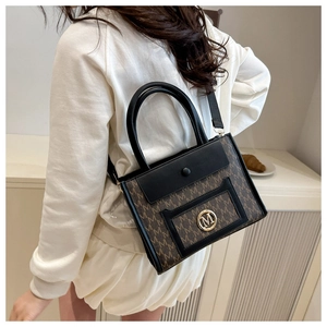 Detailed close-up of brown monogram tote bag with gold M-logo buckle and black strap