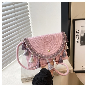 Close-up of pink woven handbag featuring bohemian embroidery and colorful fringe details