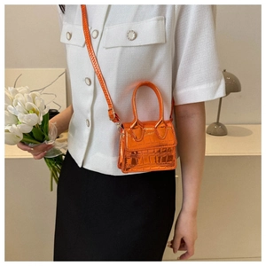 Fashionable bright orange mini square bag with crocodile pattern texture on a model