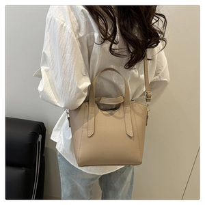 Beige bucket bag worn over the shoulder by a model in a minimalist lifestyle setting