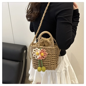 Detail of woven straw bucket bag with crochet daisies and drawstring closure lining