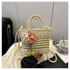 Detail of hollow-out woven straw bag with daisy charms and drawstring closure