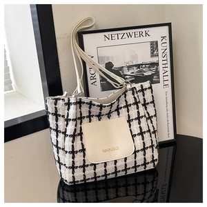 Close-up of black and white plaid tweed tote bag with leather pocket and golden text