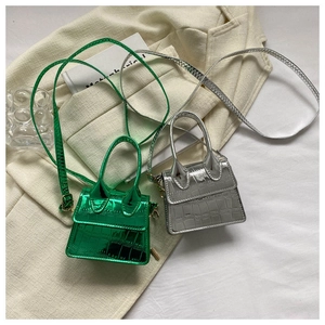 Detailed view of mini crocodile embossed top handle bags in metallic green and silver