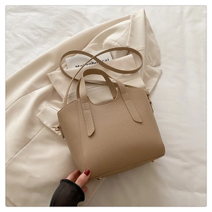 Detail view of beige lychee texture tote bag on soft fabric with gold metal feet base