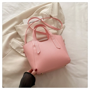 Detail view of pink leather tote bag featuring lychee texture and golden metal feet