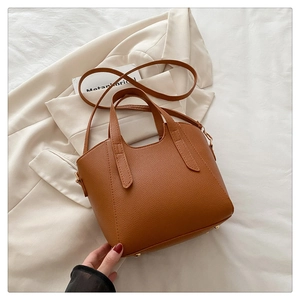 Detail of brown litchi pattern bucket bag with golden feet and detachable strap
