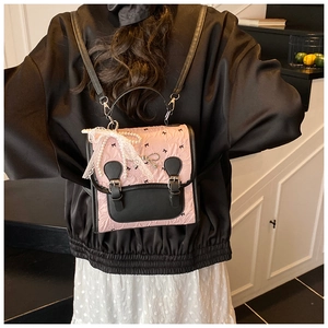 Detail eines rosa gerafften Rucksacks mit schwarzen Schleifen, Spitze und Perlenkette