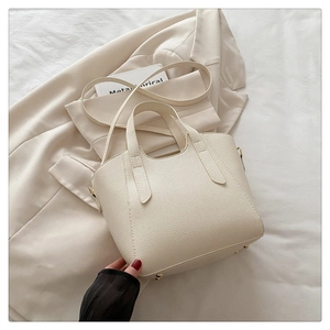 Detail of off-white lychee grain tote bag showing metal feet and detachable strap