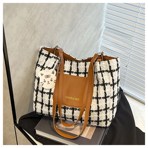 Close-up of black and white plaid tote bag with brown leather pocket and tiger charm