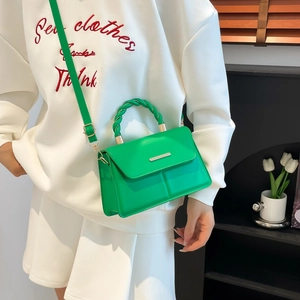 Sac à bandoulière vert vif minimaliste avec poignée tressée porté par un mannequin