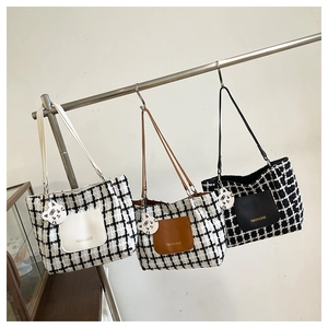 Close-up of woven checkered tote bags with leather pockets and cute cat charms