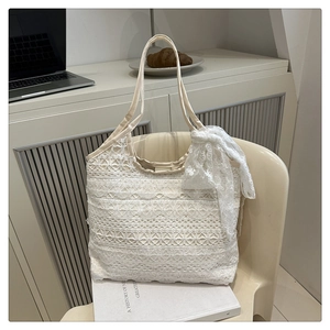 Close-up of white lace tote bag with large decorative bow and floral mesh texture