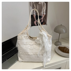 Detail of white lace tote bag with tiered crochet patterns and bow ribbon accessory