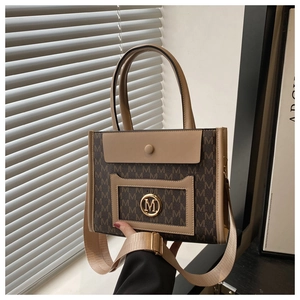 Detail of vintage monogram tote bag with gold M-logo buckle and wide woven shoulder strap
