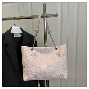 Detailed view of pink tote bag with quilted texture and colorful butterfly embroidery
