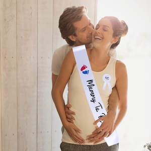 White Mommy To Be satin sash and badge set being worn at a baby shower party