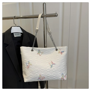 Detail of white quilted tote bag featuring colorful butterfly embroidery and chain strap