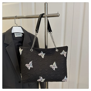Detail of black embossed tote bag featuring colorful butterfly embroidery and chain strap