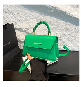 Détail du sac bandoulière vert vif avec poignée tressée et garniture dorée