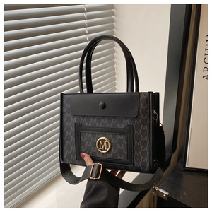 Close-up of Large tote bag with M letter print canvas and black leather magnetic flap cover
