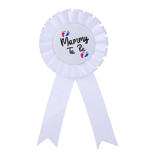 Close-up of white Mommy To Be rosette badge with baby footprints for baby shower parties