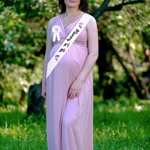 Detailed view of white Mommy To Be sash and badge set on maternity lace dress