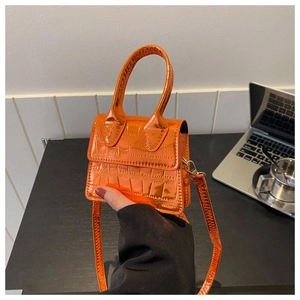 Detail of a mini orange handbag with crocodile texture and detachable shoulder strap