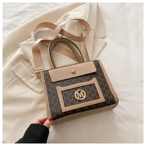 Detail of monogram patterned tote bag in brown and beige with golden logo and wide strap