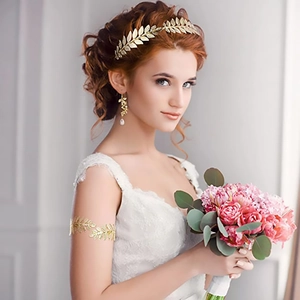 Gros plan d'une parure de mariée dorée avec couronne de feuilles, boucles et bracelet sur modèle