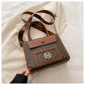 Detail view of tote bag with M-pattern monogram, gold logo and wide shoulder strap