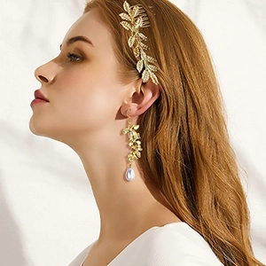 Détail d'un peigne à cheveux doré et boucles d'oreilles perles élégantes sur un modèle
