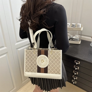 Minimalistische zweifarbige Tragetasche mit Goldprägung für Damen, als Schultertasche gezeigt