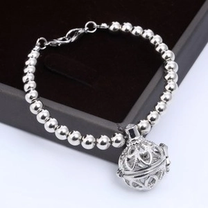 Macro detail of silver beaded bracelet with hollow filigree sphere pendant on display box