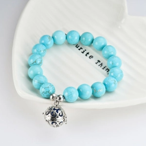 Detailed close-up of a turquoise beaded bracelet with a hollow silver sphere pendant