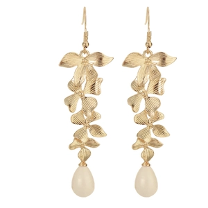 Détail de boucles d'oreilles fleuries dorées avec pétales texturés et perles blanches