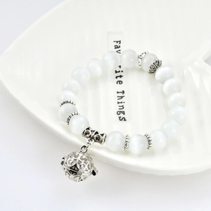Close-up of white cat eye bead bracelet with silver hollow spacers and spherical pendant