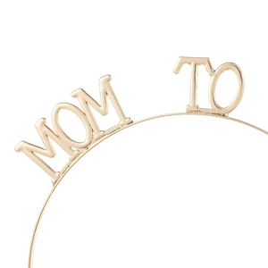 Macro detail of the golden metallic Mommy To Be headband showing refined welding crafts
