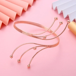Macro detail of rose gold multi-layer spiral arm cuff with round bead ends on pink background